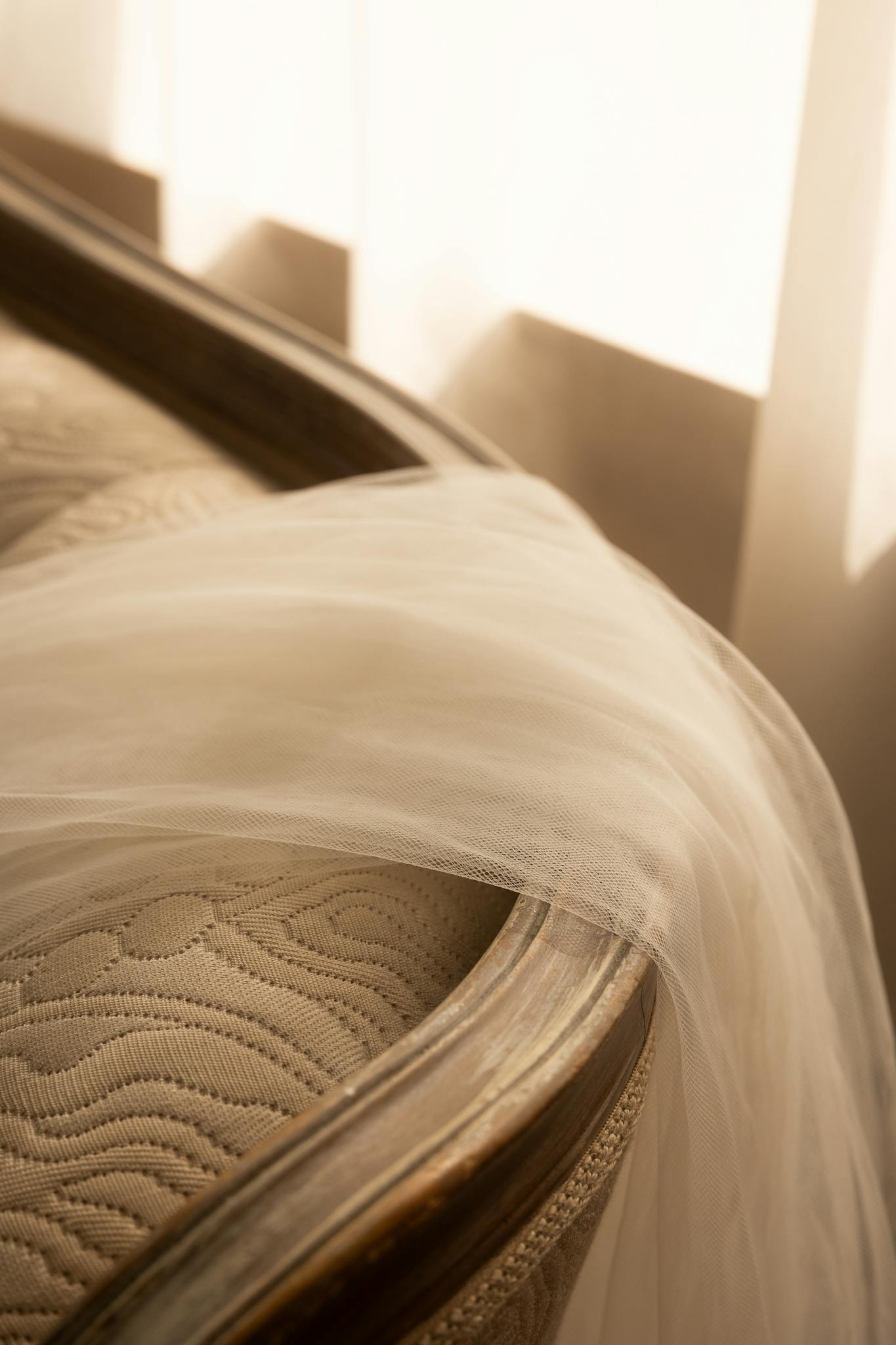 A soft bridal veil draped over a classic beige sofa in an elegant, warmly lit interior.